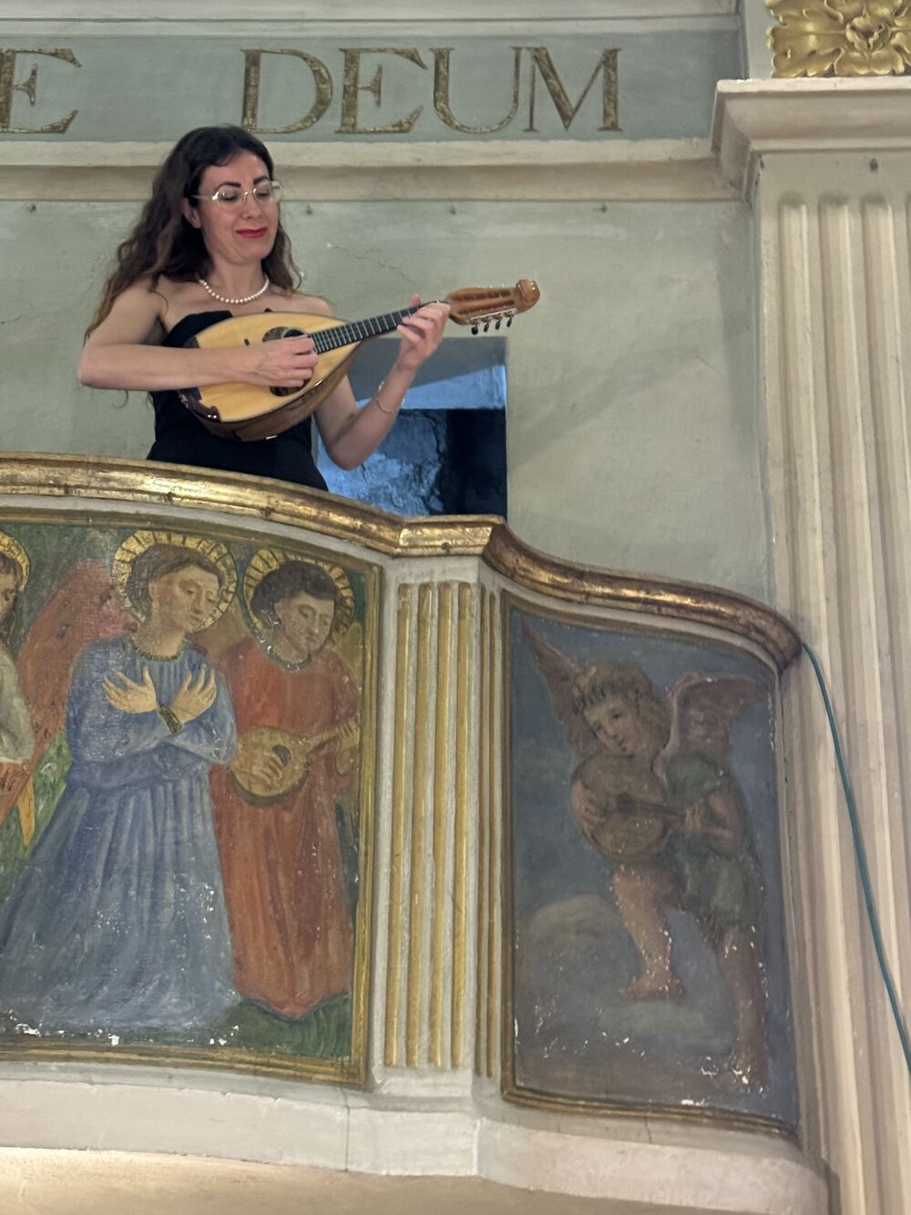 Camilla Finardi suona il mandolino da una cantoria affrescata